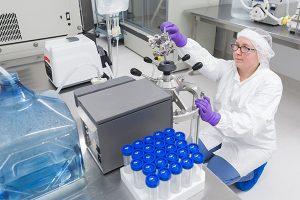 A women wearing a white lab coat sitting in front of a machine