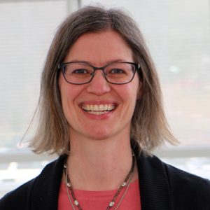 Woman with dark hair and glasses smiling