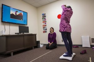 Brittany Travers observes girl as she plays a video game using the balance board.