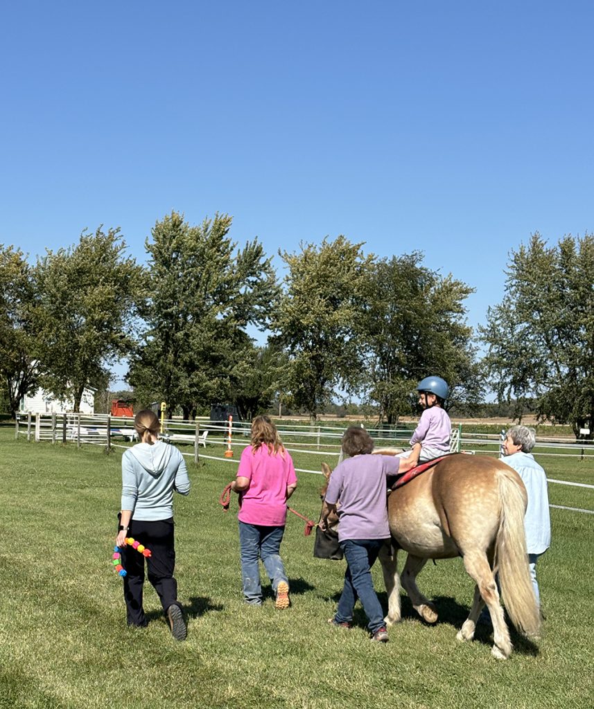 Jensen Fletcher, Elizabeth Hesse, OTD, OTR/L, Knox, and volunteers take a walk through the Three Gaits facilities