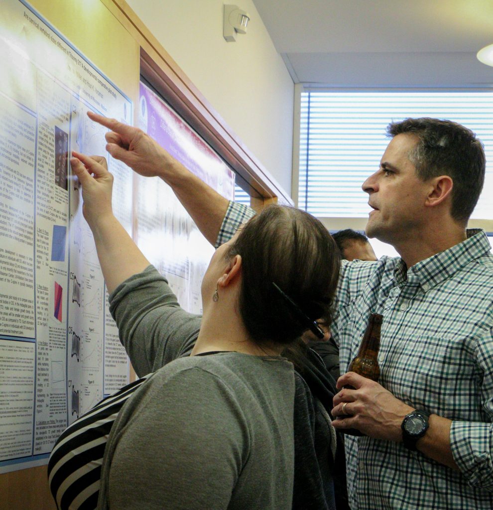 A man and a woman viewing a poster at the Waisman Center poster fair