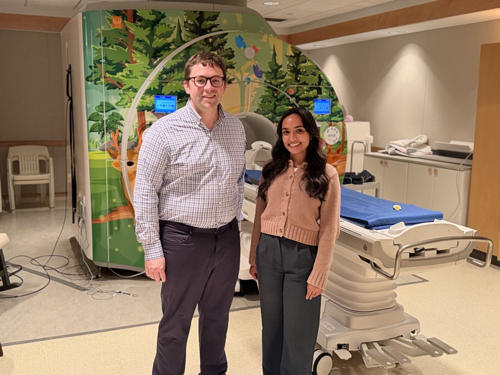 Doug and Leela stand in front of the MRI looking at the camera