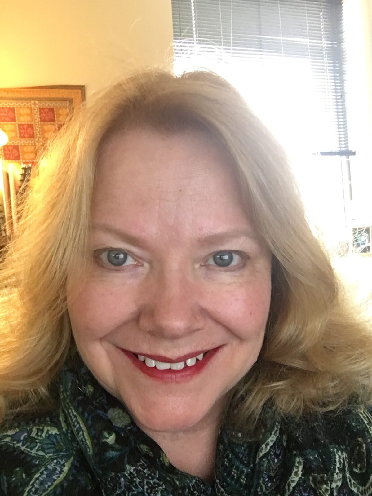 headshot of Linda (blonde with medium lenght hair) smiling at the camera wearing.